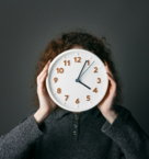 a woman covering her face with a clock